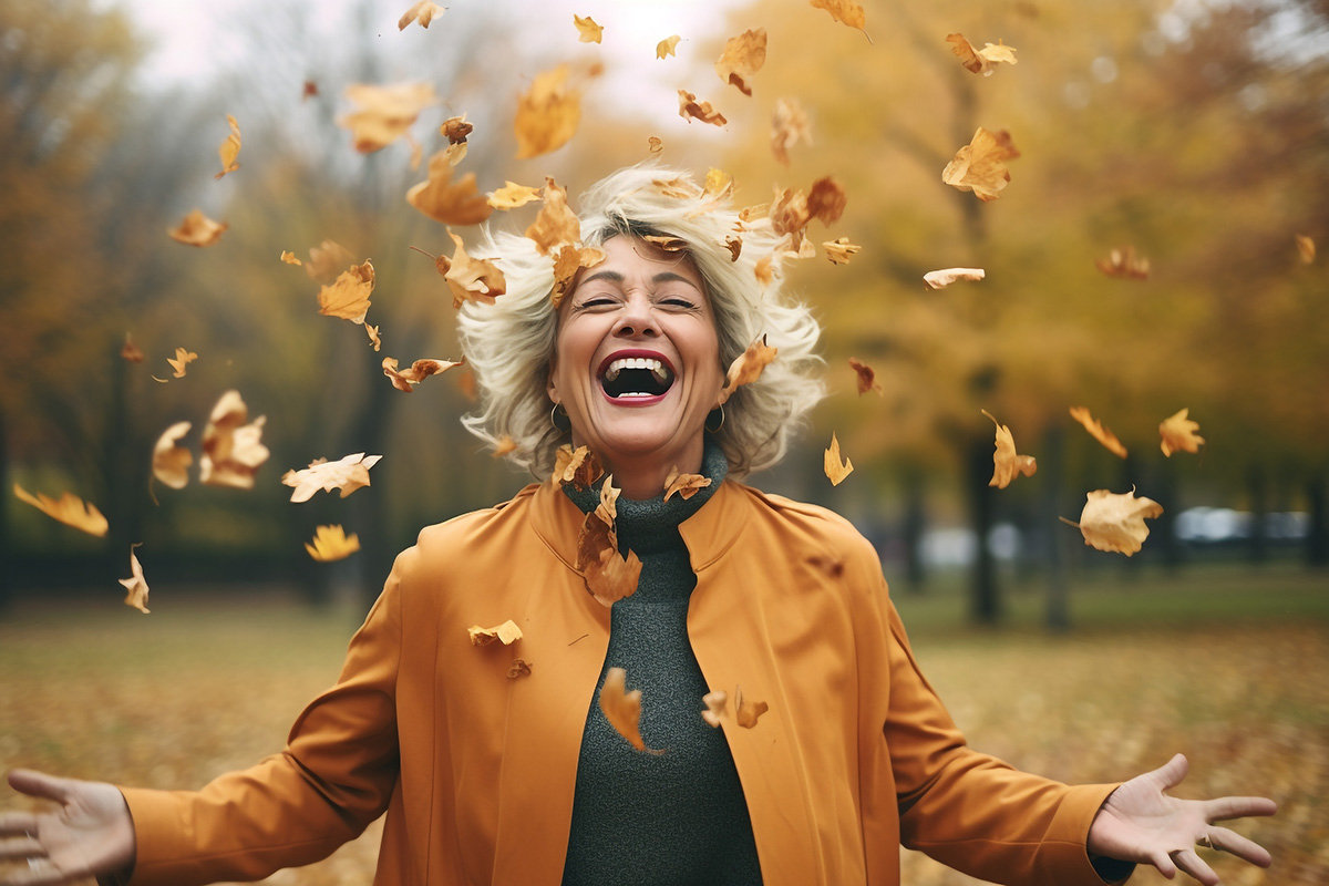 Frau wirft lachend Blätter in die Luft
